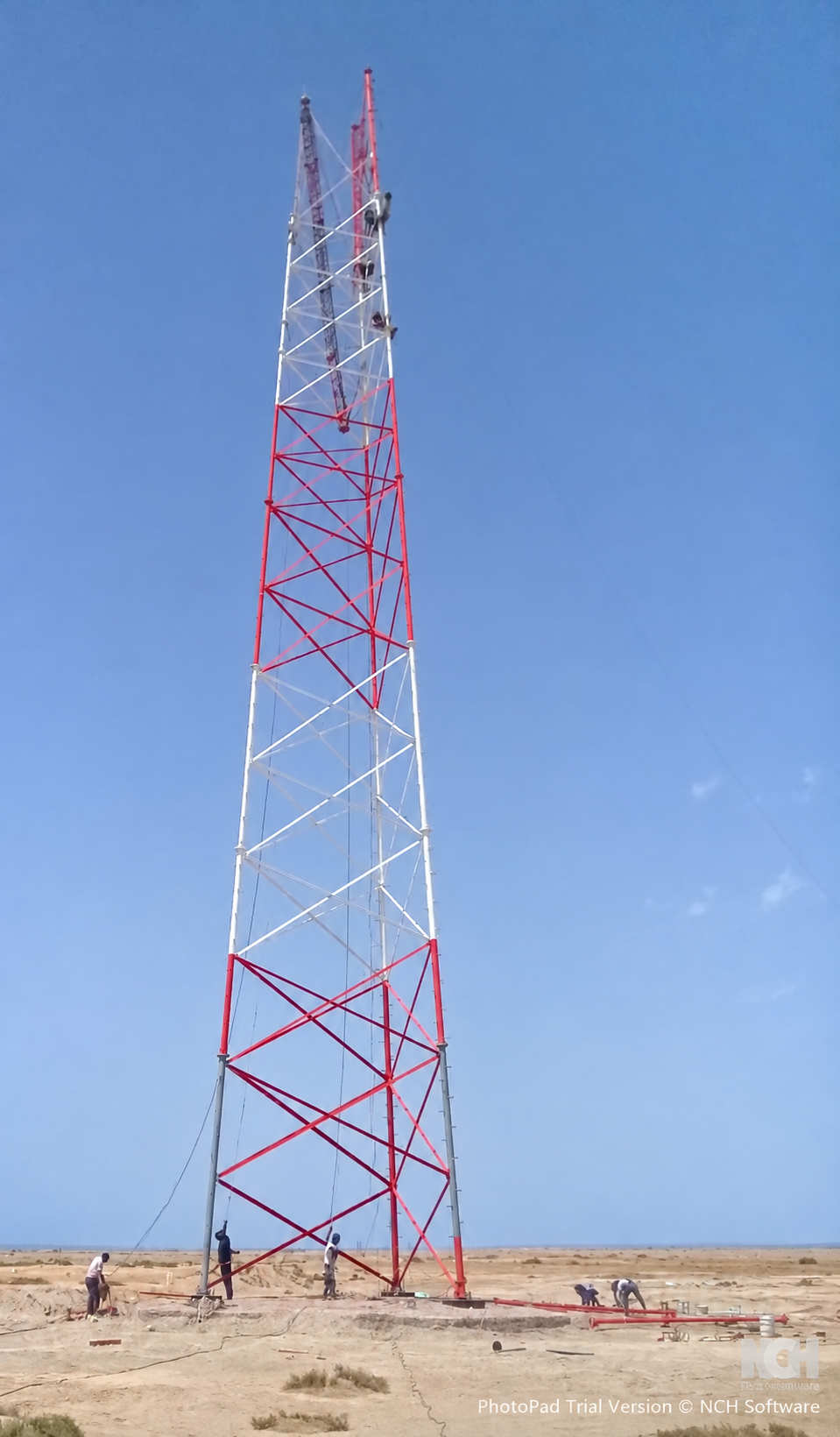 Tower erection with work continuing at height and at ground level.