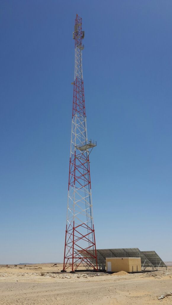 Completed tower with adjacent equipment shelter and solar panels.
